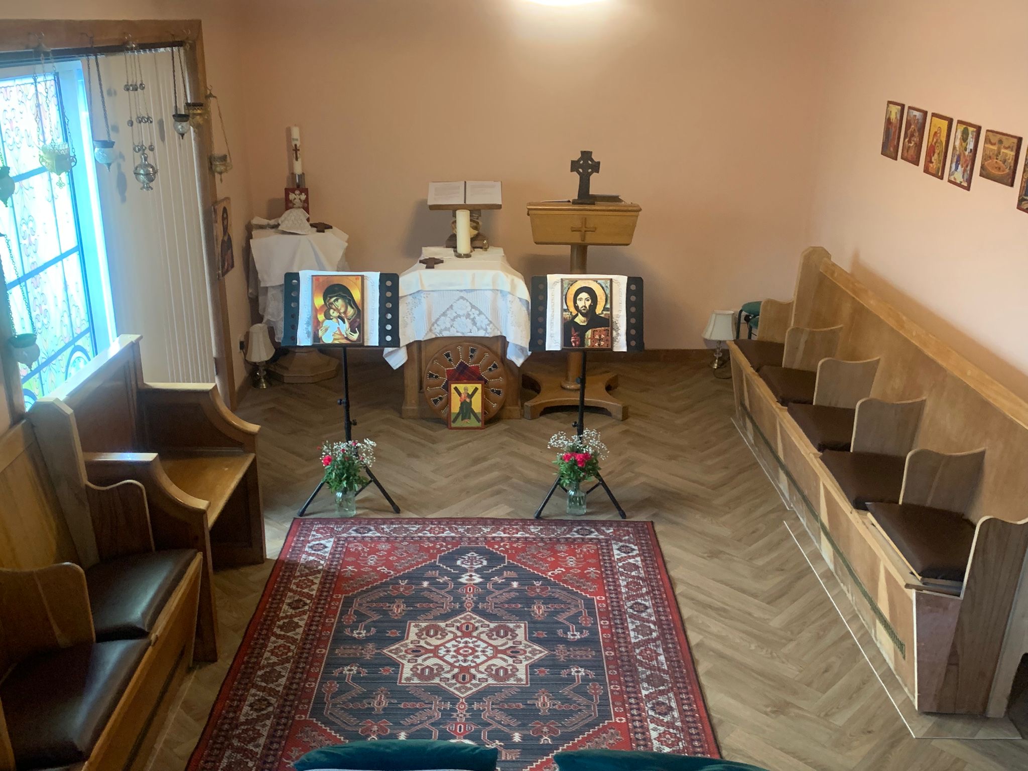 The chapel interior showing the altar, the lectern with the Celtic cross, the Christ Pantocrator and the Theotokos on the chanter stands, the tartan roundel with the icon of Saint Fillan, and the pews